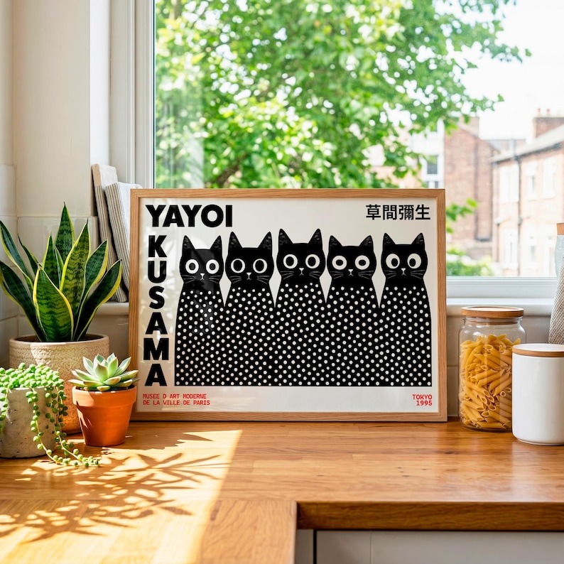 May include: A rectangular framed art print featuring five black cats with large white eyes and white polka-dot bodies. The text YAYOI KUSAMA is printed vertically in black on the left, with Japanese characters and TOKYO 1995 at the bottom.