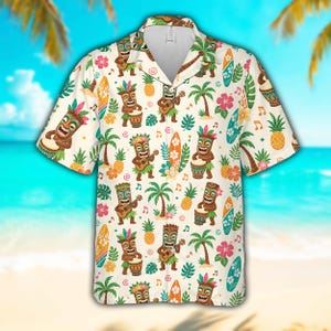 Op de afbeelding: Crèmekleurig Hawaiiaans overhemd met een herhalend patroon van cartoon tiki-figuren die instrumenten bespelen, palmbomen, surfplanken, ananassen en bloemen. Het overhemd heeft korte mouwen en een knoopsluiting, ideaal voor een vakantie.
