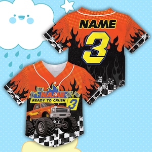 May include: Orange and black baseball jersey with a monster truck graphic. The jersey features the number 3 in yellow, the word "NAME" above the number, and the words "READY TO CRUSH" with a checkered flag design. The jersey has a white collar.