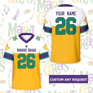 May include: A white, gold, and purple Mardi Gras jersey with the number 26 in green. The front of the jersey reads "Mardi Gras" above the number. The back of the jersey has space for a name and the number 26.