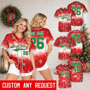 Può includere: Una maglia da baseball rossa e bianca con motivo a fiocchi di neve, il testo Merry Christmas, il numero 26 e un'area per il nome personalizzabile. La camicia ha un'abbottonatura frontale, maniche corte e finiture verdi.