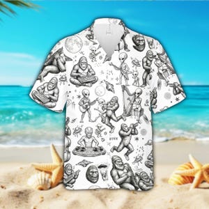 May include: White short-sleeve button-down shirt with a repeating black and white pattern of aliens, Bigfoot, musical instruments, and UFOs. The shirt features a classic collar and a relaxed fit, perfect for casual wear.