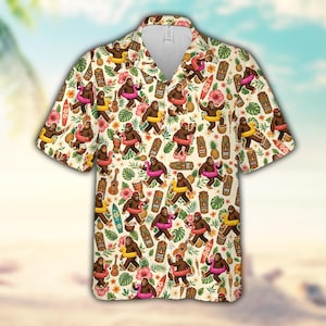 May include: A short-sleeve button-down shirt with a cream background featuring a repeating pattern of brown bigfoot creatures wearing colorful inflatable pool rings, tiki statues, pineapples, ukuleles, surfboards, and pink hibiscus flowers.