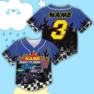 May include: Blue baseball jersey with a monster truck graphic. The jersey features the text "NAME" above the number "3" in yellow. The phrase "READY TO CRUSH" is also visible. Flames and a checkered pattern are incorporated into the design.