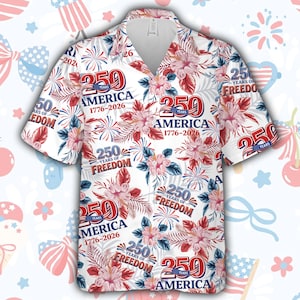 Puede incluir: Camisa blanca con botones con un estampado floral y de fuegos artificiales. La camisa presenta el texto "250 YEARS AMERICA 1776-2026" y "250 YEARS OF FREEDOM" en rojo y azul. El diseño incluye flores de hibisco y elementos patrióticos.