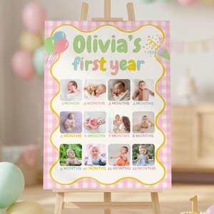以下が含まれることがあります： イーゼルに立てられたピンクと白のチェック柄のポスターで、「Olivia's first year」の文字と、さまざまな年齢の赤ちゃんの写真が掲載されています。ポスターには風船とパーティーホーンのグラフィックが含まれています。