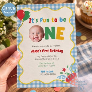 May include: A rectangular first birthday invitation card featuring a blue and white gingham border, a photo of a baby, and colorful text that reads It's Fun to be ONE, Jason's First Birthday, 123 Somuchfun St., December 18, and RSVP to Jack 123-456-7890.