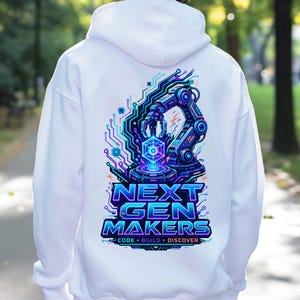 May include: A white hooded sweatshirt featuring a vibrant back graphic of a robotic arm interacting with a glowing cube. The design includes circuit board patterns in blue, purple, and cyan, with the text NEXT GEN MAKERS CODE BUILD DISCOVER.