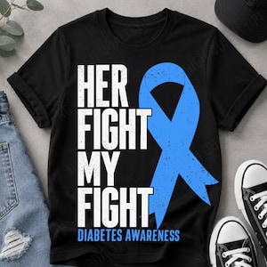 Puede incluir: Una camiseta negra de manga corta con el texto blanco desgastado "HER FIGHT MY FIGHT" apilado verticalmente junto a un gran lazo azul de concienciación. La parte inferior de la camiseta muestra el texto azul "DIABETES AWARENESS".