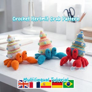 May include: Three colorful crochet hermit crabs with striped shells and orange, blue, and red bodies. The text "Crochet Hermit Crab Pattern" is displayed above the crabs. The image also includes the text "Multilingual Tutorial".