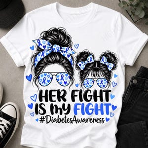 Puede incluir: Una camiseta blanca con un gráfico de dos figuras con moños, diademas con estampado de corazones azules y gafas de sol con estampado de corazones azules. El texto dice: HER FIGHT IS MY FIGHT #DiabetesAwareness, rodeado de pequeños corazones azules.
