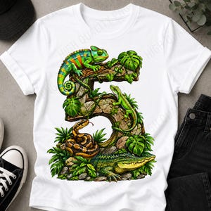 Könnte beinhalten: Ein weißes T-Shirt mit einer großen Grafik der Zahl Fünf, die aus strukturiertem Stein und üppigen grünen Tropenblättern besteht. Das Design zeigt ein buntes Chamäleon, eine grüne Eidechse, eine geringelte braune Schlange und ein Krokodil.