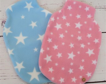 May include: Two fleece hot water bottle covers. One is light blue with white stars, the other is pink with white stars. A small wooden button is on the pink cover. The covers are on a light wood grain surface.