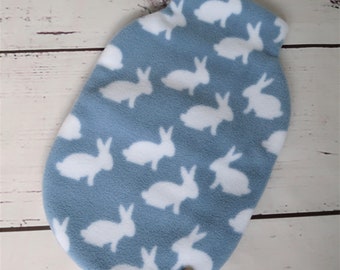 May include: A blue fleece hot water bottle cover with a white bunny rabbit pattern. The cover has a button closure.