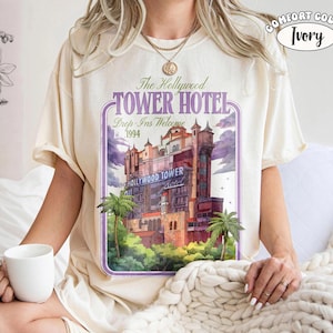 Op de afbeelding: Ivoor kleurig T-shirt met een afbeelding van het Hollywood Tower Hotel met de tekst "The Hollywood Tower Hotel Drop-Ins Welcome 1994". Het shirt is van het merk Comfort Color.
