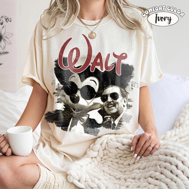 Puede incluir: Camiseta de color marfil con un gr&aacute;fico de Mickey Mouse con gafas de sol y Walt Disney. La palabra "Walt" est&aacute; impresa en rojo encima de la imagen. La camiseta est&aacute; etiquetada como "Comfort Color Ivory".