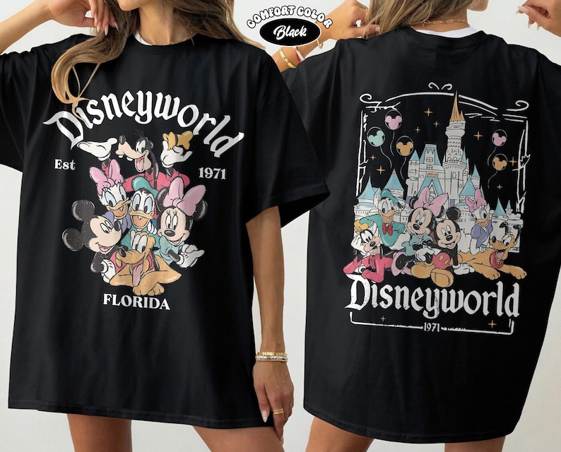 K&ouml;nnte beinhalten: Ein schwarzes T-Shirt mit einer Vorderseite, die Mickey Mouse, Minnie Mouse, Donald Duck, Daisy Duck, Goofy und Pluto mit dem Text Disneyworld Est 1971 Florida zeigt. Die R&uuml;ckseite zeigt dieselben Figuren vor einem Schloss mit Luftballons.