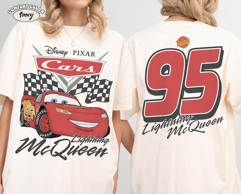 Może przedstawiać: Kremowa koszulka z Lightning McQueen z filmu Auta Disneya Pixara. Grafika z przodu zawiera logo Auta, szachownice i uśmiechnięty czerwony samoch&oacute;d wyścigowy. Tył przedstawia dużą czerwoną liczbę 95 i napis "Lightning McQueen."