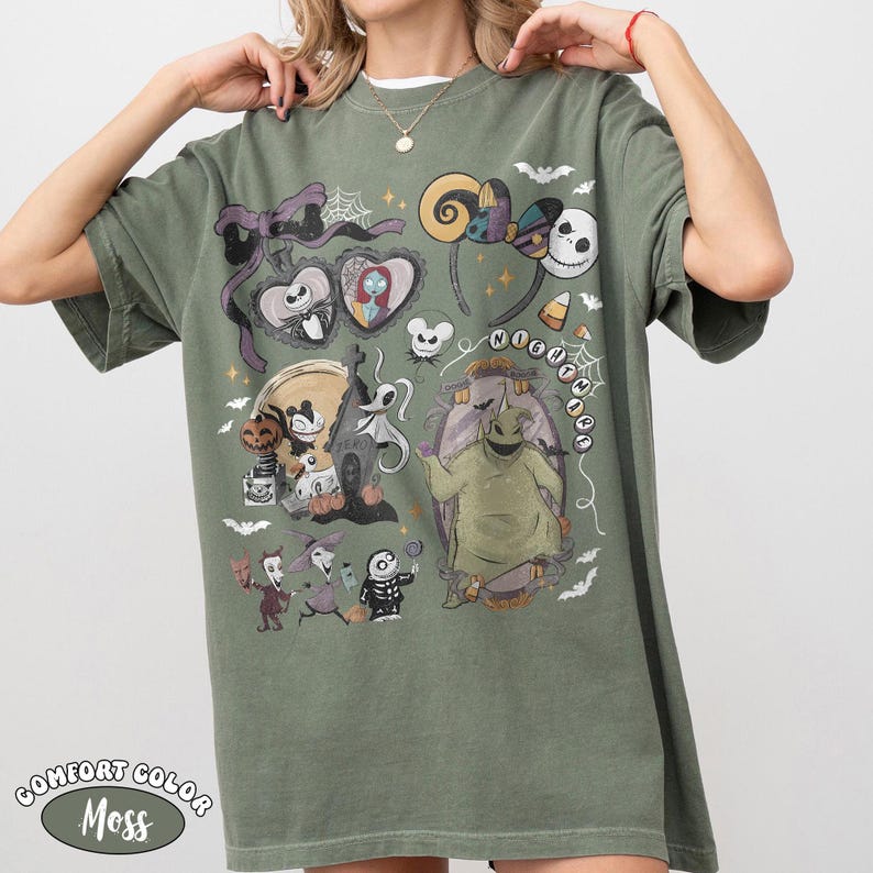 May include: An olive green t-shirt featuring a graphic print of characters and motifs from The Nightmare Before Christmas, including Jack Skellington, Sally, Oogie Boogie, Zero, and various spooky elements like spiderwebs, bats, and candy corn.