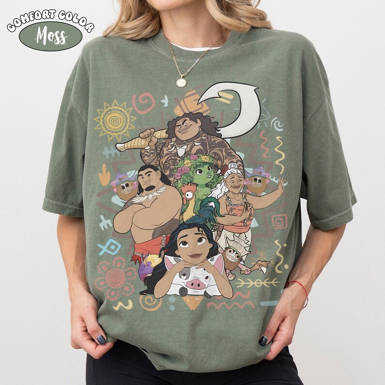 Puede incluir: Una camiseta de manga corta color verde musgo con un estampado gr&aacute;fico de personajes de la pel&iacute;cula Moana, incluyendo a Maui, Moana, Pua, Heihei y Gramma Tala, rodeados de varios s&iacute;mbolos tribales y un icono de gancho blanco.