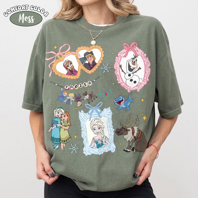 May include: Moss green Comfort Colors t-shirt featuring various characters and elements from the animated film "Frozen." The design includes framed portraits of characters, snowflakes, and the word "FROZEN" in a banner.