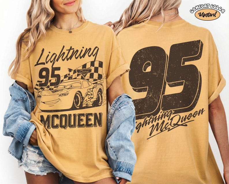 May include: Mustard-colored t-shirt featuring a graphic of Lightning McQueen from the movie Cars. The front design includes the text "Lightning 95 McQueen" and an image of the race car. The back of the shirt displays a large "95" and "Lightning McQueen".