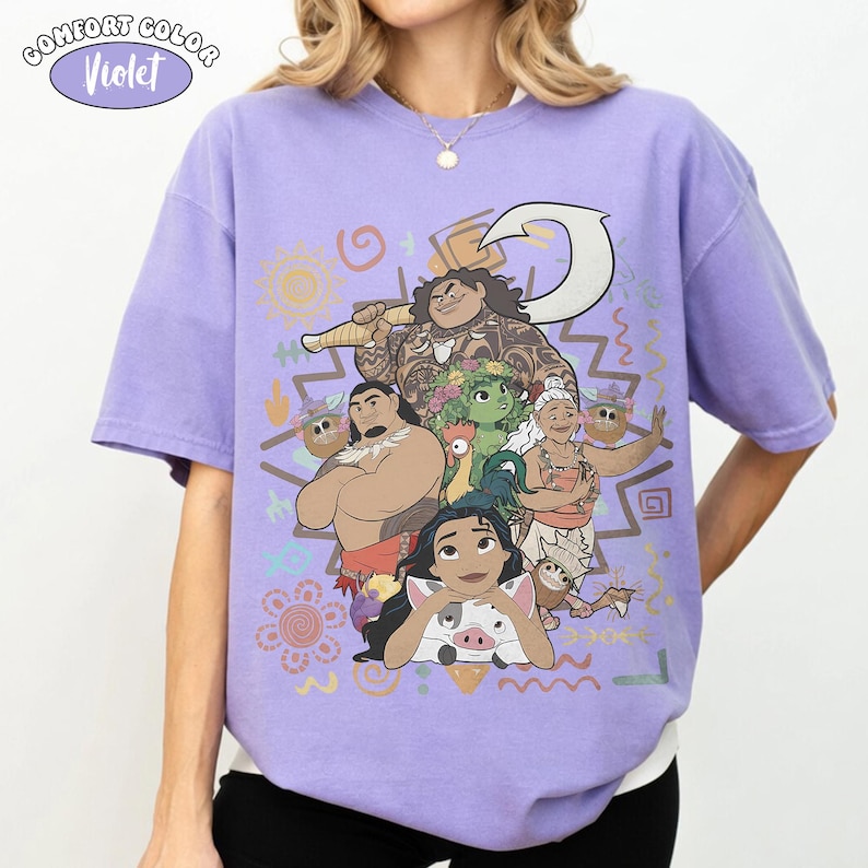 Puede incluir: Una camiseta violeta de manga corta con un estampado gr&aacute;fico de personajes de la pel&iacute;cula Moana, incluyendo a Moana, Maui, Pua, Heihei y la abuela Tala, rodeados de varios s&iacute;mbolos de inspiraci&oacute;n tribal y un icono grande de un anzuelo blanco.