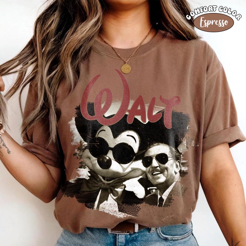 Puede incluir: Camiseta color espresso con un gr&aacute;fico de Mickey Mouse con gafas de sol y Walt Disney. La palabra "WALT" est&aacute; impresa en color granate sobre la imagen. La camiseta est&aacute; etiquetada como "COMFORT COLOR" y "Espresso".