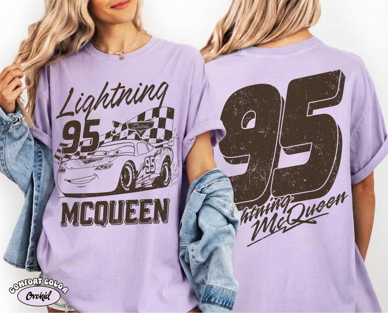 May include: A light purple t-shirt featuring a graphic of Lightning McQueen race car with the number 95 and the text "Lightning McQueen". The back of the shirt displays a large number 95 and "Lightning McQueen".
