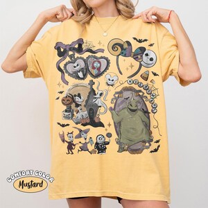 May include: A mustard yellow t-shirt featuring a graphic print of characters and icons from The Nightmare Before Christmas, including Jack Skellington, Sally, Oogie Boogie, Zero, and various spooky elements like tombstones, bats, and candy corn.
