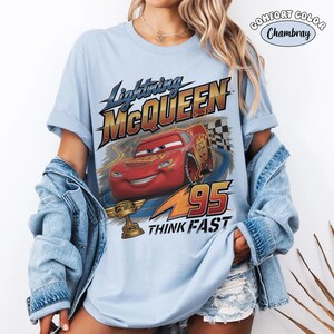 May include: Light blue t-shirt featuring Lightning McQueen from the Cars movie. The graphic includes the text "Lightning McQueen", the number "95", and the phrase "Think Fast". The shirt is a Comfort Colors Chambray.