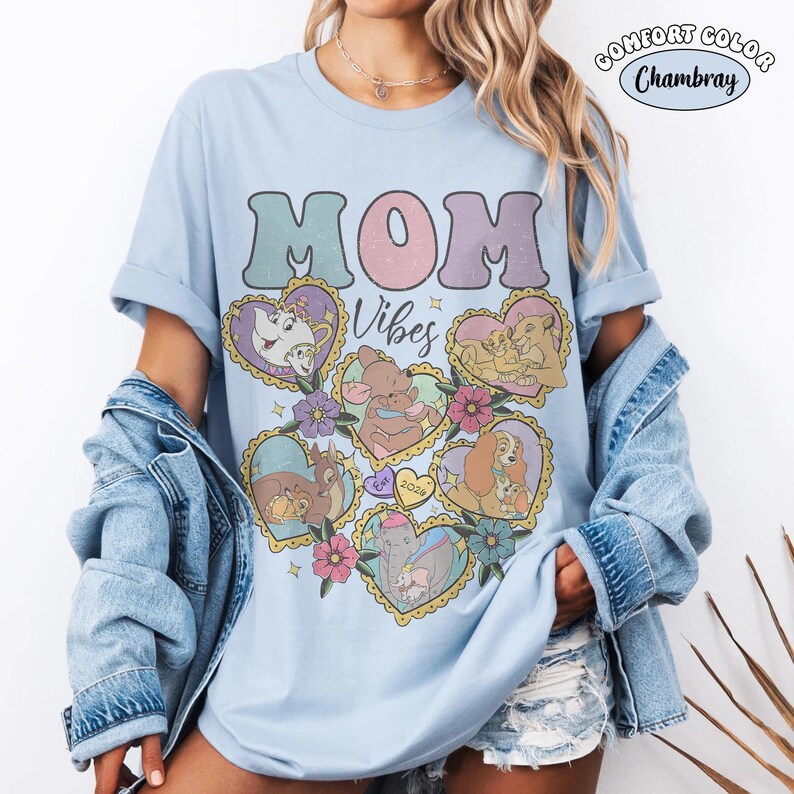 Pu&ograve; includere: T-shirt azzurra Comfort Colors Chambray con le parole "MOM Vibes" in un font retr&ograve;. La maglietta presenta illustrazioni a forma di cuore di personaggi Disney. La maglietta &egrave; a girocollo e maniche corte.