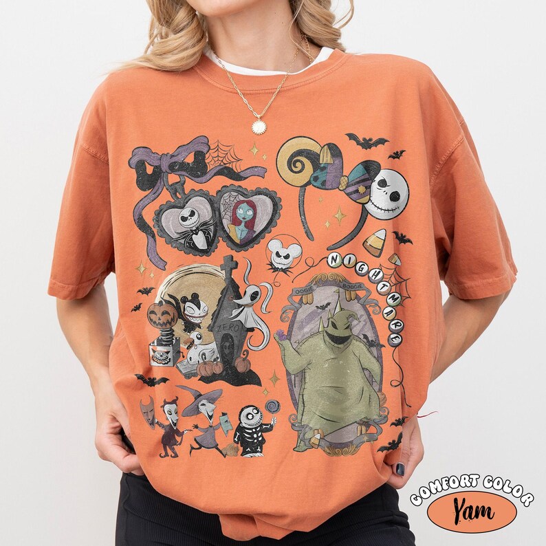 May include: An orange short-sleeve t-shirt featuring a graphic print of characters from The Nightmare Before Christmas, including Jack Skellington, Sally, Zero, and Oogie Boogie, alongside various Halloween-themed icons and decorative elements.