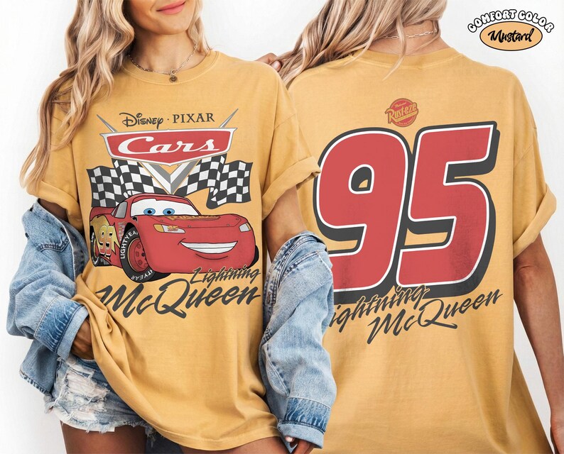 Może przedstawiać: Musztardowa koszulka z Lightning McQueen z filmu Auta Disneya Pixara. Prz&oacute;d przedstawia logo Cars, szachownicę i Lightning McQueen. Tył pokazuje dużą liczbę 95 i napis "Lightning McQueen."