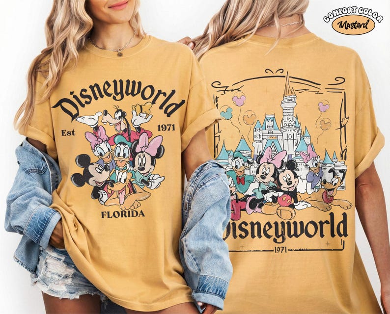 K&ouml;nnte beinhalten: Ein senfgelbes T-Shirt mit einer Grafik von Disney-Figuren, darunter Mickey Maus, Minnie Maus, Donald Duck, Daisy Duck, Goofy und Pluto. Die Vorderseite zeigt den Text Disneyworld Est 1971 Florida. Die R&uuml;ckseite zeigt das Schloss.