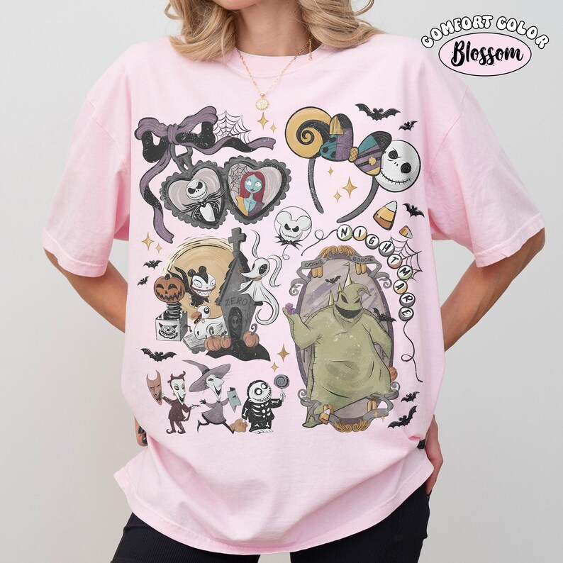 May include: A light pink t-shirt featuring a graphic print of characters and icons from The Nightmare Before Christmas, including Jack Skellington, Sally, Zero, and Oogie Boogie, with a Comfort Color Blossom logo in the top right corner.