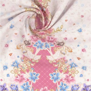 Peut inclure: Tissu floral avec un motif répété de fleurs roses, bleues et violettes sur fond blanc. Le motif comprend des accents dorés et un panneau central rose avec un motif en losange. Le tissu est plié, révélant sa texture.