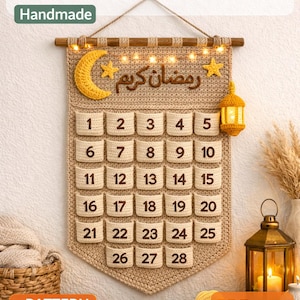 May include: A handmade crochet Ramadan Advent Calendar with a beige background. The calendar features 28 numbered pockets, a crescent moon, stars, and a lantern. The text "Ramadan Kareem" is displayed in Arabic. The top banner reads "CROCHET Ramadan Advent Calendar Handmade".
