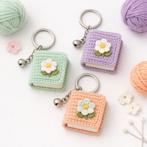 以下が含まれることがあります： パステルカラーの手編みブックキーホルダー。ミントグリーン、ラベンダー、ピーチの3色。各キーホルダーには小さなベルと、白い中心を持つかぎ針編みの花が付いています。シルバーのキーリングに取り付けられています。