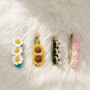 Può includere: Quattro spille fatte a mano all'uncinetto con disegni floreali. Le spille presentano margherite, girasoli, api e rose in vari colori. Ogni spilla è attaccata a una spilla da balia.