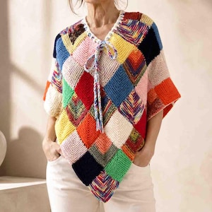 May include: A knitted poncho featuring a multi-colored diamond pattern in shades of red, blue, yellow, green, orange, and cream. The garment has a V-neckline with a braided drawstring tie and short sleeves, constructed from individual square patches.