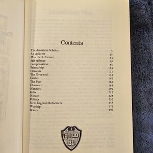 May include: Open book page with the title "Contents" and a list of chapter titles, including "The American Scholar" and "Man the Reformer." A small emblem is at the bottom of the page.