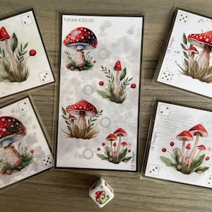 Op de afbeelding: Een verzameling kunstprints met paddenstoelen en een dobbelsteen. De prints tonen rood-wit gevlekte paddenstoelen met groene bladeren. De dobbelsteen heeft paddenstoelillustraties. De tekst "Totaal €50,00" is zichtbaar.