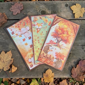 Op de afbeelding: Drie rechthoekige gelamineerde spelkaarten met herfstillustraties van een muis, een vos en een egel. Elke kaart toont gekleurde herfstbladeren, genummerde cirkels voor het bijhouden van scores en de tekst Totaal en Totaal 50.