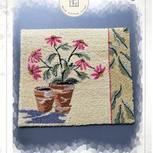 Peut inclure: Modèle de point d'aiguille pour une centaurée en pot. Le motif présente un fond beige clair avec une seule plante en pot avec des fleurs roses et des feuilles vertes. Le motif est encadré par une bordure bleu clair avec une bordure verte et blanche sur le côté droit.