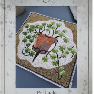 Può includere: Modello di punto ad ago per un vaso di fiori con foglie verdi. Il modello si chiama "Pot Luck" ed è stato progettato da Kate Gillery. Il modello è largo 19 cm e alto 19 cm.