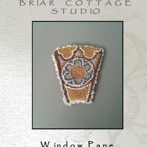 Puede incluir: Un patrón de punto de aguja o de bordado para un panel de ventana. El patrón es un diseño geométrico con un esquema de color marrón, amarillo y azul. El patrón se titula "Window Pane" y es de Briar Cottage Studio.