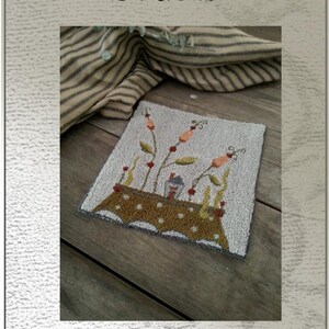 May include: Punch needle or needlework design pattern for a tiny cottage with a brown table and orange flowers. The pattern is called "Tiny Cottage" and is by Briar Cottage Studio. The pattern measures 5.5 inches by 5.5 inches.