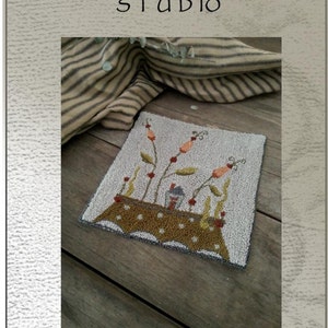 May include: Punch needle or needlework design pattern for a tiny cottage with a brown table and orange flowers. The pattern is called "Tiny Cottage" and is by Briar Cottage Studio. The pattern measures 5.5 inches by 5.5 inches.
