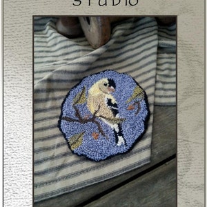 Peut inclure: Un modèle de point d'aiguille ou de broderie pour un chardonneret sur une branche. Le modèle s'appelle "Goldfinch Ornie" et est conçu par Kate Gillery. Le modèle mesure 10 cm sur 9 cm.